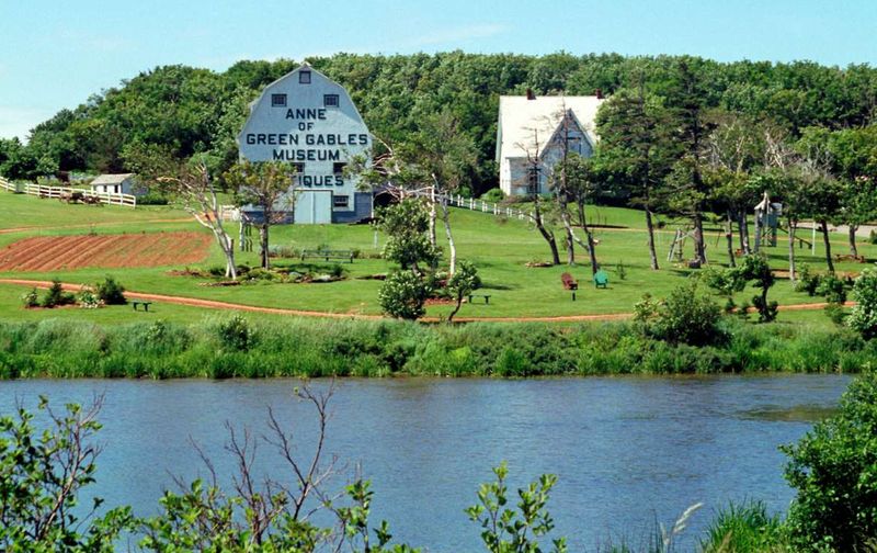 The Anne of Green Gables Museum and rural landscape in Prince Edward Island viewed across a body of water.