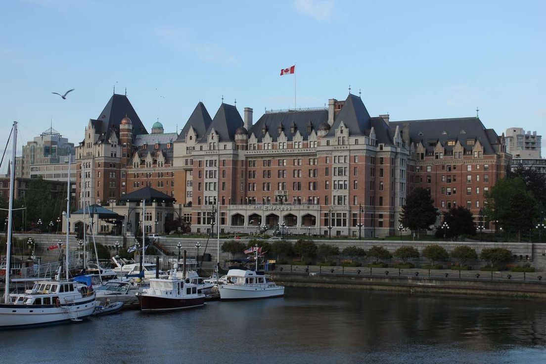 The Fairmont Empress hotel in Victoria, British Columbia, viewed across a harbor with docked boats.
