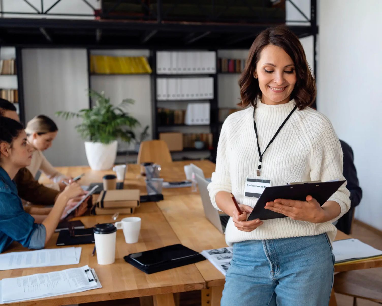 Woman holding clipboard in an office setting, representing applicants in Canada working under a Bridging Open Work Permit while awaiting permanent residency decision