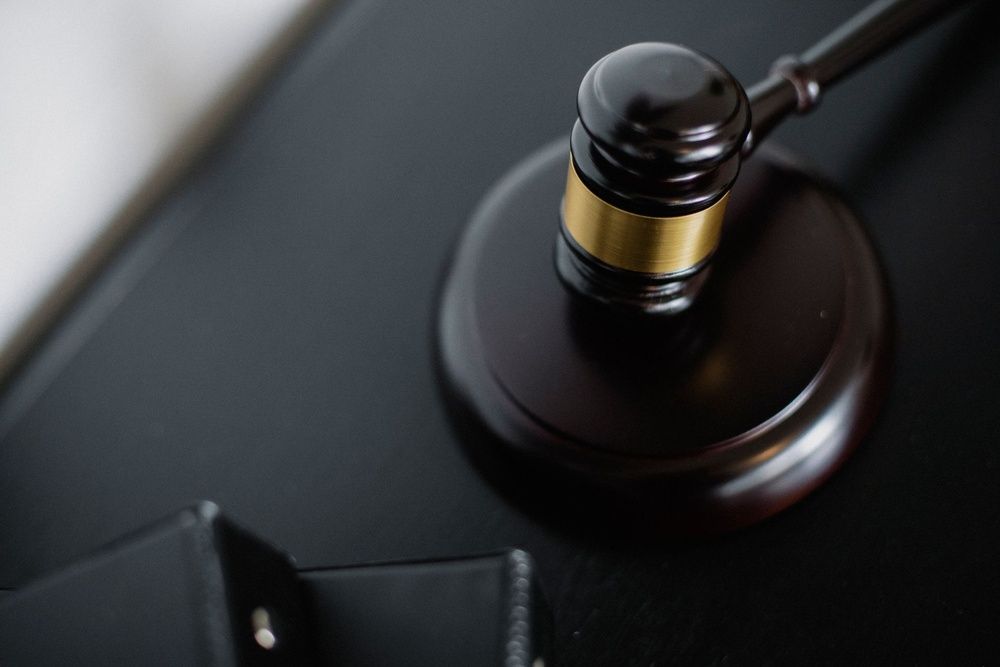 A wooden judge's gavel with a gold band resting on its sound block.