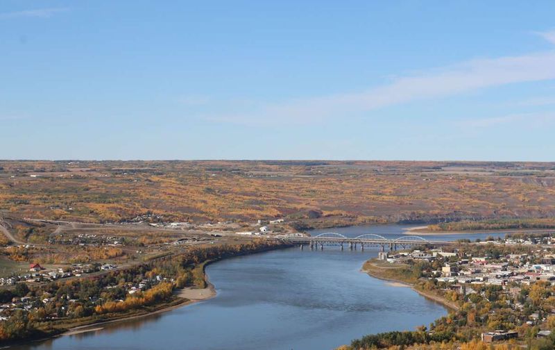 Aerial view of a wide river winding through a small town surrounded by colorful autumn foliage.