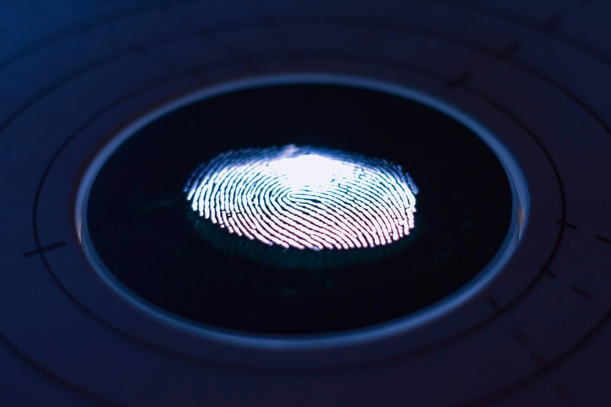 A glowing fingerprint scan illuminated on a dark circular biometric scanner.