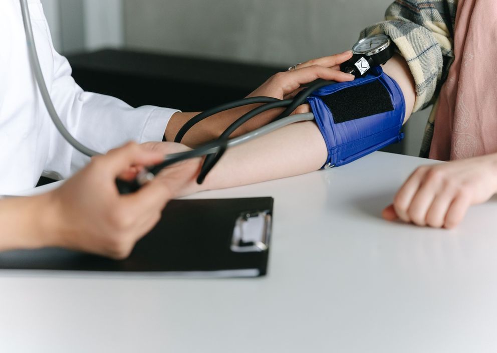 A healthcare provider measuring a patient's blood pressure with a manual cuff.