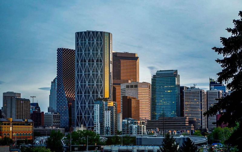 Modern downtown Calgary skyline featuring tall glass skyscrapers under a blue sky.