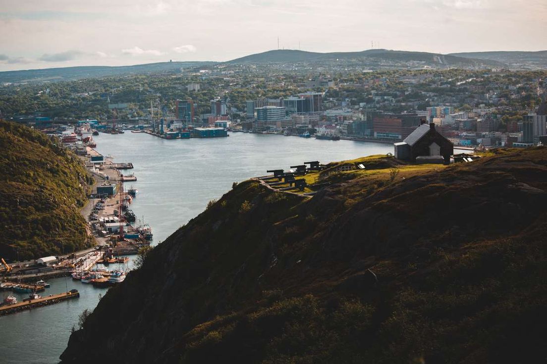 Elevated view of St. John's harbor and city skyline in Newfoundland from a hilltop with cannons.